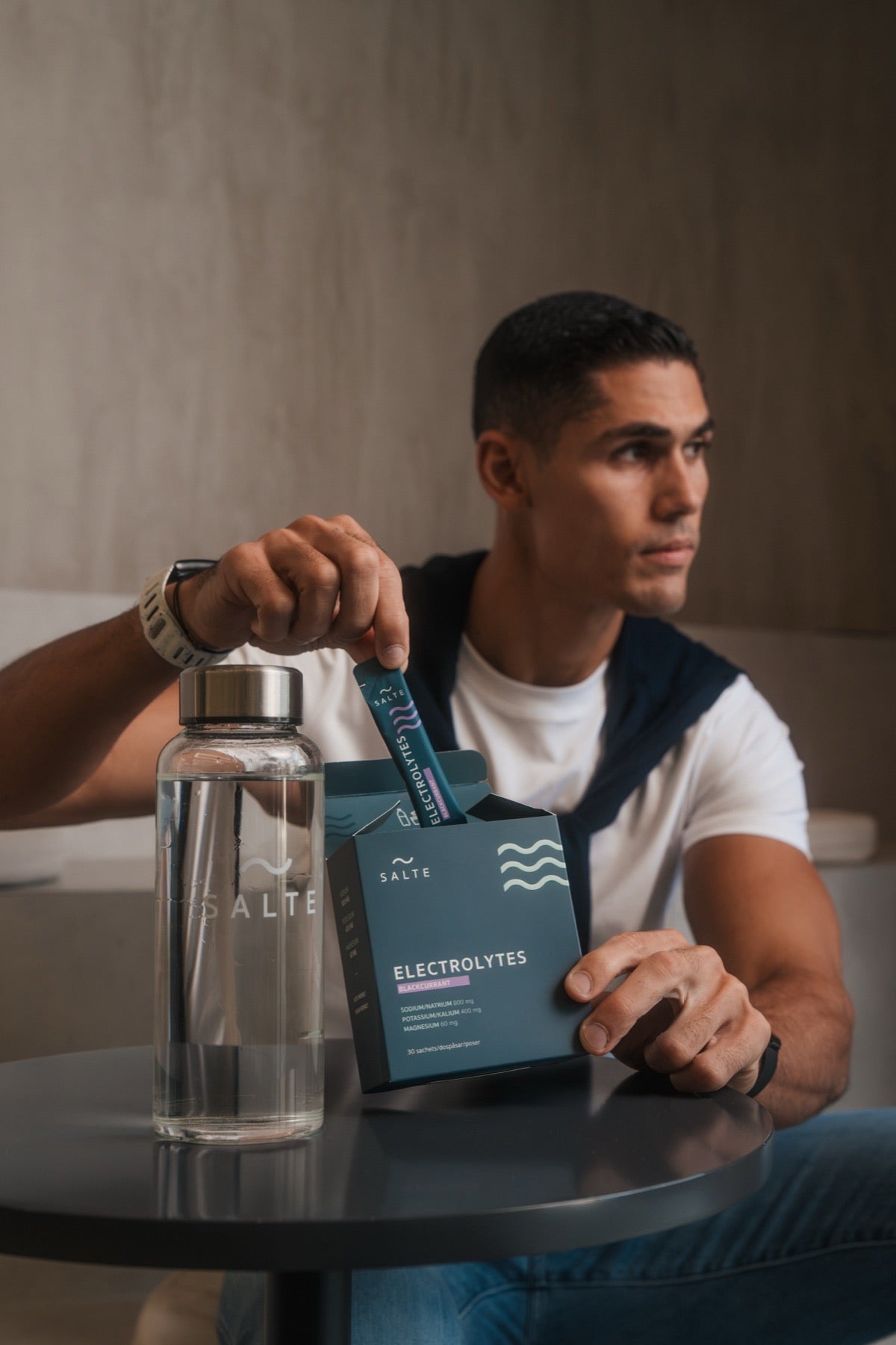 Man pouring SALTE into a glass bottle at a café table